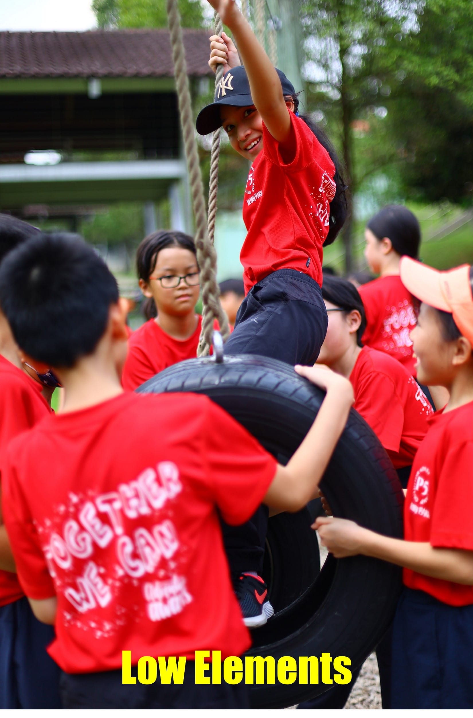 A P5 student on the tyre swing with her group mates surrounding her